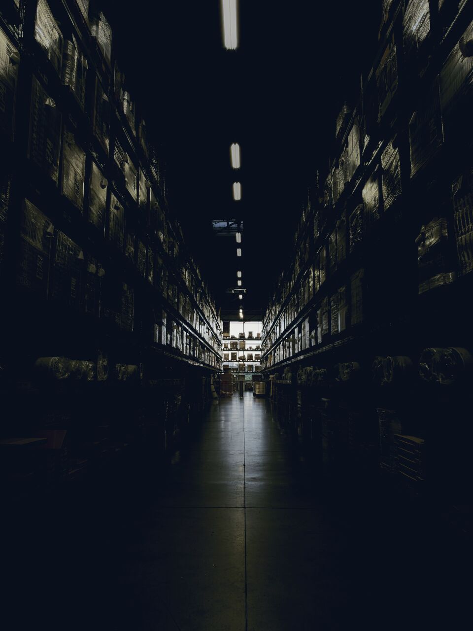 Dim one-point-perspective warehouse aisle