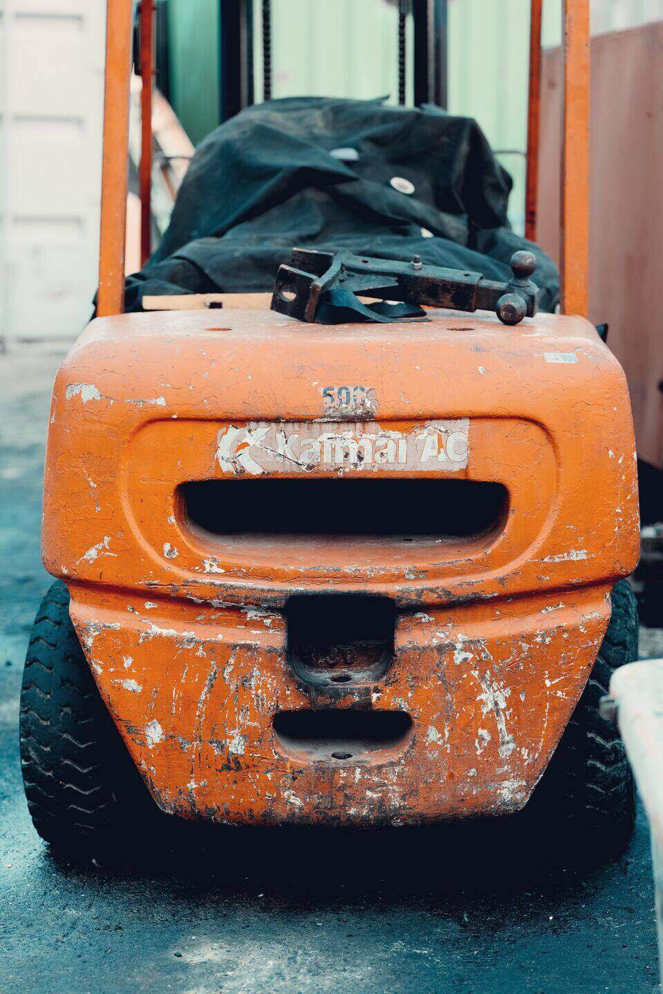Orange forklift moving a pallet in low light