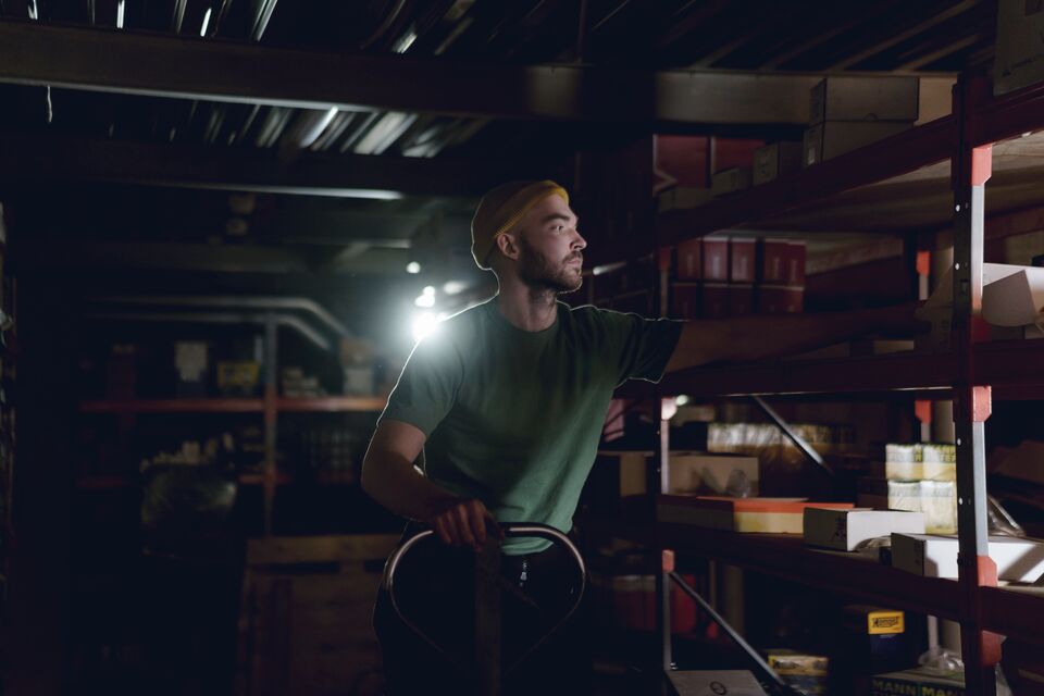 Worker pulling stock from dark shelving
