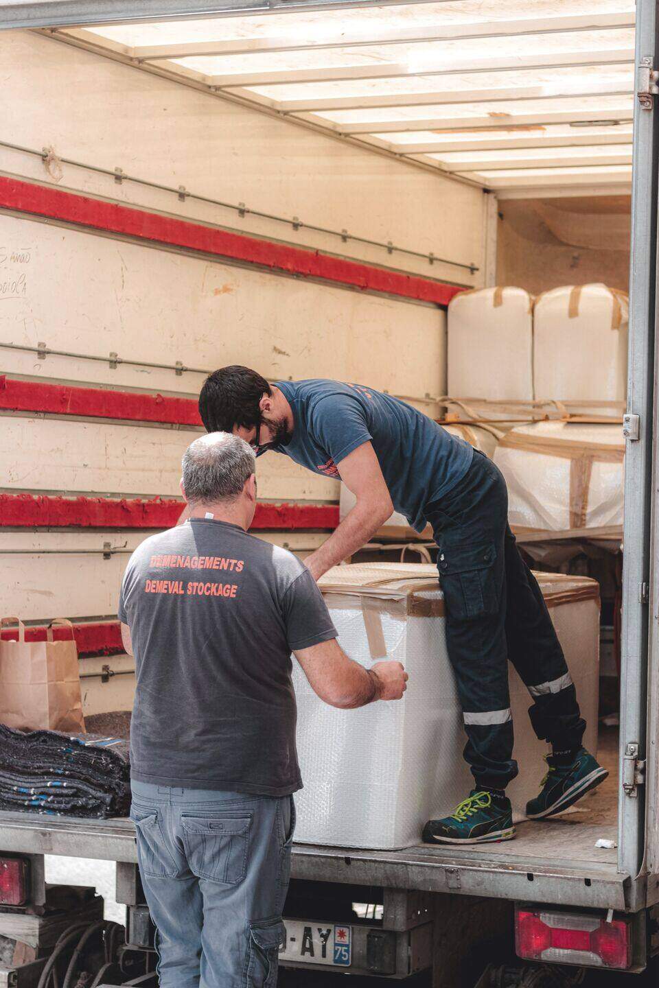 Two workers unloading boxes at a truck tailgate