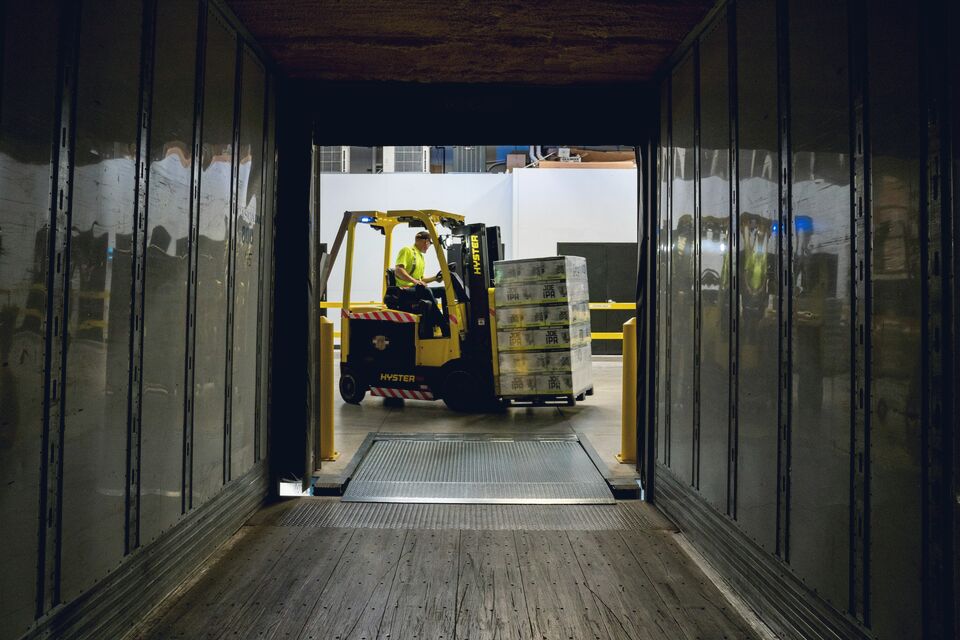 Worker beside a forklift in a low-lit warehouse