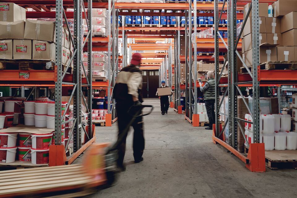 Worker moving a wrapped pallet with a hand truck